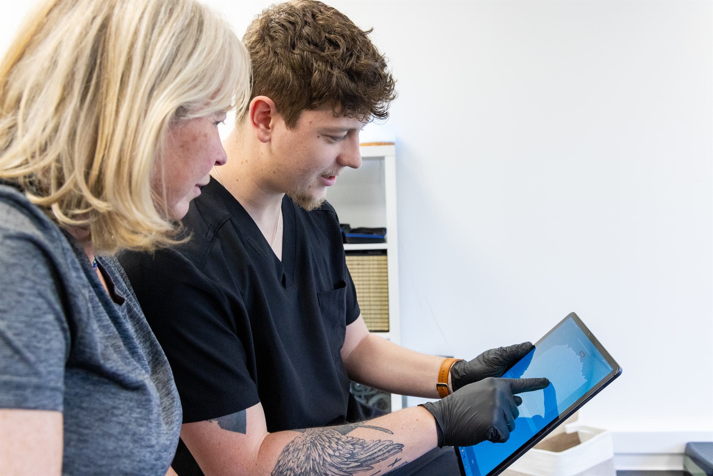 Physiotherapist reviewing assessment results on a tablet with a patient at the Norwich clinic